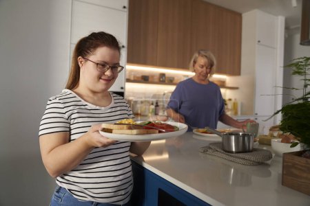 Photo for Down syndrome woman serving breakfast - Royalty Free Image