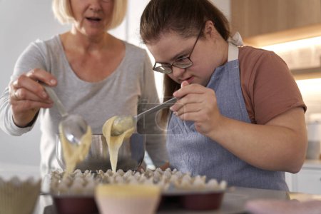 Foto de Síndrome de Down mujer y su madre haciendo cupcakes caseros - Imagen libre de derechos