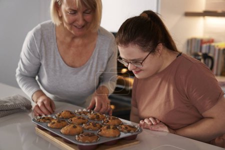 Téléchargez les photos : Femme trisomique et mère sur le point de manger des cupcakes faits maison - en image libre de droit