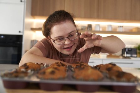 Téléchargez les photos : Femme trisomique ne peut pas résister aux cupcakes maison - en image libre de droit