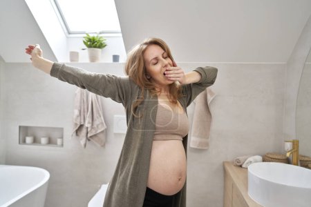 Photo for Caucasian pregnant woman stretching in the morning in the bathroom - Royalty Free Image