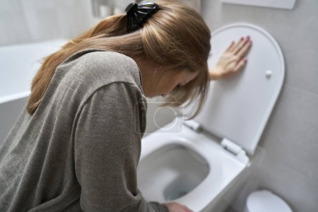 Téléchargez les photos : Femme se penchant sur les toilettes et ayant une nausée - en image libre de droit