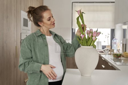 Photo for Pregnant woman taking care of flowers at home - Royalty Free Image