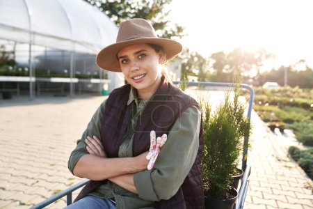 Portrait of female plant nursery worker sitting on transport trolley