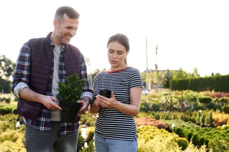 Téléchargez les photos : Travailleur conseillant le client sur les plantes dans le centre de jardin - en image libre de droit