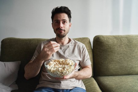 Téléchargez les photos : Homme manger du pop-corn et regarder la télévision - en image libre de droit