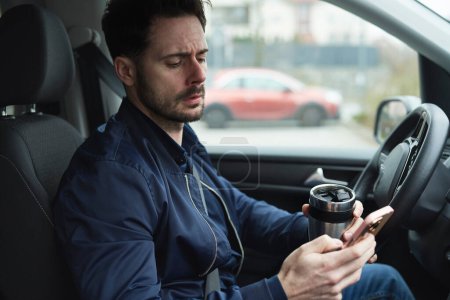 Téléchargez les photos : Homme utilisant tasse réutilisable et téléphone dans la voiture - en image libre de droit