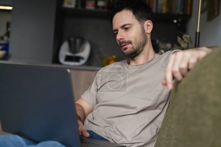 Téléchargez les photos : Homme travaillant sur ordinateur portable sur canapé - en image libre de droit
