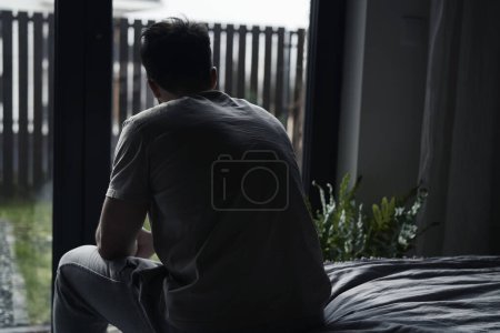 Téléchargez les photos : Vue arrière de l'homme déprimé à la maison - en image libre de droit