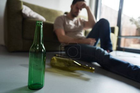 Foto de Hombre borracho sentado en el suelo entre botellas vacías - Imagen libre de derechos
