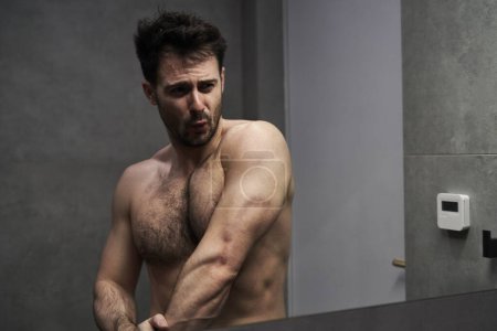 Photo for Caucasian man flexing muscles in the mirror - Royalty Free Image