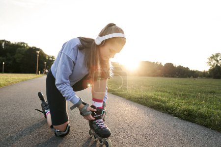 Photo for Woman preparing to rollerblade in the park - Royalty Free Image