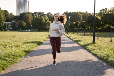 Photo for Wide shot of woman jogging in the park during sunset - Royalty Free Image