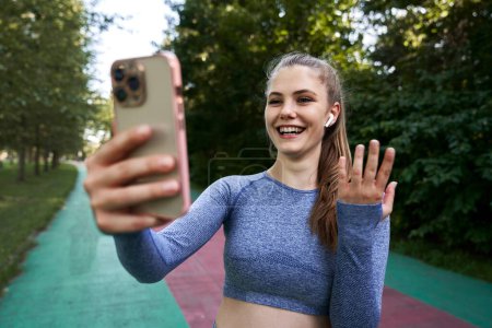 Foto de Mujer en ropa deportiva en la pista sosteniendo un teléfono móvil - Imagen libre de derechos