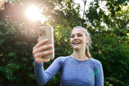 Téléchargez les photos : Femme en tenue de sport sur piste tenant un téléphone portable - en image libre de droit