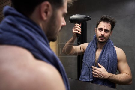 Téléchargez les photos : Homme caucasien sèche-cheveux dans la salle de bain - en image libre de droit