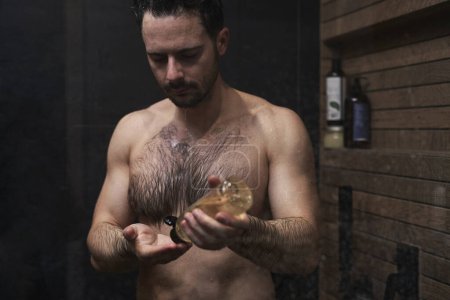 Foto de Caucásico hombre usando champú bajo la ducha - Imagen libre de derechos
