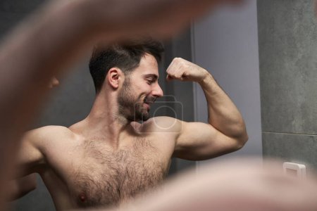 Téléchargez les photos : Homme caucasien flexion des muscles dans le miroir - en image libre de droit