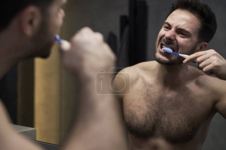 Téléchargez les photos : Homme brossant les dents dans la salle de bain domestique - en image libre de droit