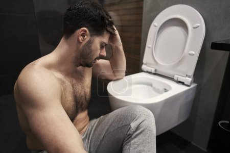 Foto de Hombre enfermo con dolor de estómago al lado del inodoro - Imagen libre de derechos