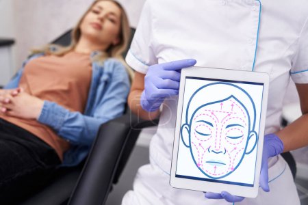 Téléchargez les photos : Médecin présentant tablette numérique avec croquis de lifting du visage - en image libre de droit