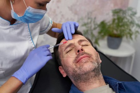 Foto de Hombre que tiene procedimiento de lifting facial en el salón de belleza - Imagen libre de derechos