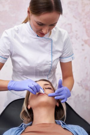 Téléchargez les photos : Esthéticienne nettoyant le visage du patient avant la procédure de beauté - en image libre de droit