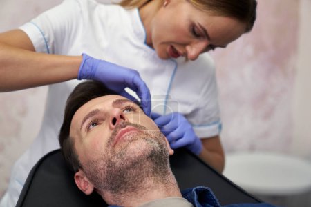 Foto de Hombre que tiene procedimiento de lifting facial en salón de belleza - Imagen libre de derechos
