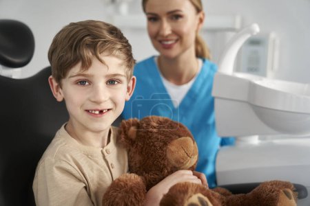 Téléchargez les photos : Enfant tenant un ours en peluche au cabinet du dentiste - en image libre de droit