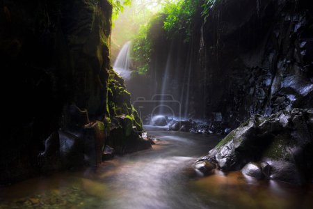 Téléchargez les photos : Visitez le charme de l'Indonésie avec la cascade Lorong Watu, au nord du Bengkulu. Une ruelle étroite bordée de murs de pierre, la lumière du matin brille sur la cascade - en image libre de droit
