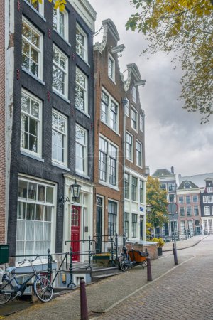 Photo for Netherlands. Sunny day in Amsterdam. Sloping facades of authentic Dutch houses and antique street lamps - Royalty Free Image
