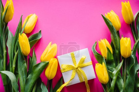 Photo for Yellow tulips with gift box on pink background. Space for message. Flowers concept. Holiday greeting card for Valentine's, Women's, Mother's Day, Easter. Birthday. Place for text. Top view, flat lay. - Royalty Free Image
