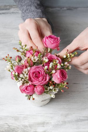 Photo for Woman is making a floral decoration with roses and chamelaucium. Hobby time - Royalty Free Image