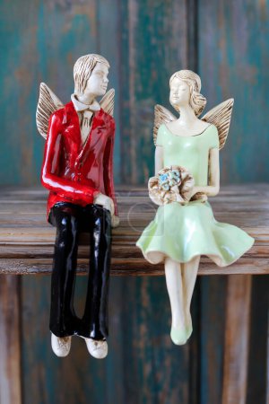 Two angels - boy and girl, sitting on a wooden table. Home decor
