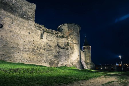 Téléchargez les photos : Vue sur les tours et les murs du château Kamianets-Podilskyi dans la nuit. Bastion en pierre d'un ancien château. Beau château en pierre sur la colline la nuit. Ukraine - en image libre de droit