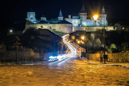 Téléchargez les photos : Vue sur le château de Kamianets-Podilskyi dans la nuit. Beau château en pierre sur la colline la nuit. Longue exposition. Illumination du château. Ukraine - en image libre de droit