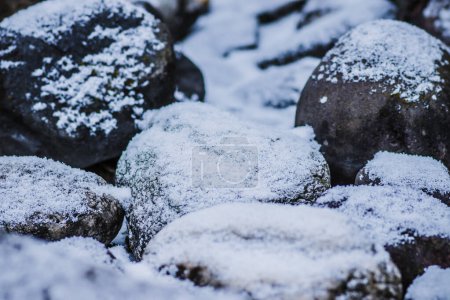 Téléchargez les photos : Pierres pour une petite clôture dans le jardin dans la neige. Pierre naturelle dans la neige. Photo de haute qualité - en image libre de droit