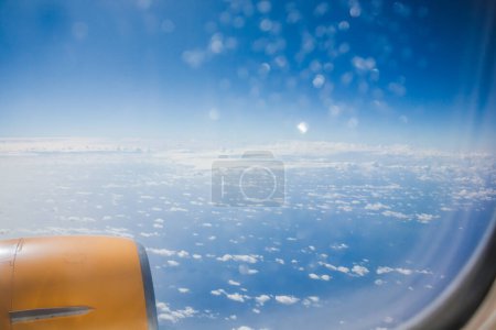 Above the clouds, the wing of an airplane is visible in the sky, showcasing the vast expanse of the atmosphere during air travel