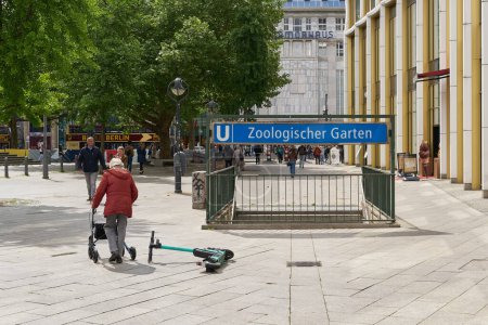 Téléchargez les photos : Berlin, Allemagne 28 mai 2022 : couché e-scooter et femme âgée à la station de métro Zoologischer Garten à Breitscheidplatz à Berlin - en image libre de droit