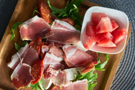 Photo for Hearty snack in a restaurant in Italy with ham, salami, rocket and cheese and a bowl of melon - Royalty Free Image