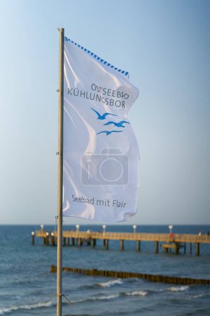Photo for Kuehlungsborn, Germany  May 26, 2023: Flag on the beach of the Baltic Sea with the german inscription Ostseebad Kuehlungsborn, Seebad mit Flair. Translation: Baltic resort Kuehlungsborn, seaside resort with flair - Royalty Free Image
