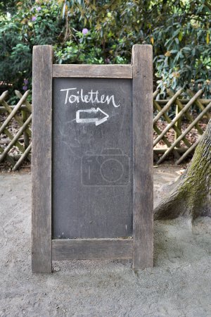 Téléchargez les photos : Panneau avec flèche de direction pour toilettes dans un jardin de bière à Berlin en Allemagne - en image libre de droit
