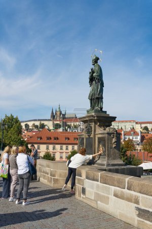 Foto de Praga, República Checa Octubre 02, 2023: Turistas frente a la estatua de San Nepomuk en el Puente de Carlos de Praga - Imagen libre de derechos