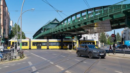 Photo for Berlin, Germany  May 30, 2023: Street scene in Berlin's Prenzlauer Berg district with car, elevated train and streetcar - Royalty Free Image