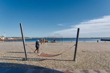 Téléchargez les photos : Stralsund, Allemagne 30 octobre 2023 : Hamac et quelques touristes sur la promenade portuaire rénovée de Stralsund sur le Strelasund en Allemagne - en image libre de droit