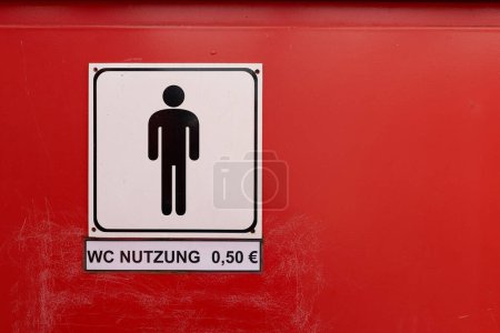  Schild mit der deutschen Aufschrift WC Nutzung 0,50 an einer Herrentoilette. Übersetzung: WC use 0,50                               