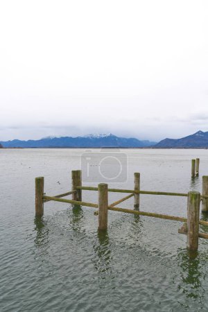 Remains of an old landing stage for boats in Prien am Chiemsee with the Chiemgau Alps in the background                               