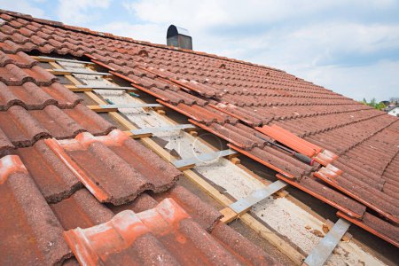Photo for Uncovered house roof, broken shingles to replace after a storm damage. blue sky background - Royalty Free Image