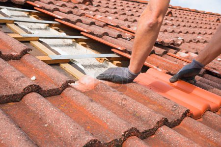 Photo for Man replaces broken roof shingles on the rooftop with new ones. closeup shot, picture section with only the arms - Royalty Free Image