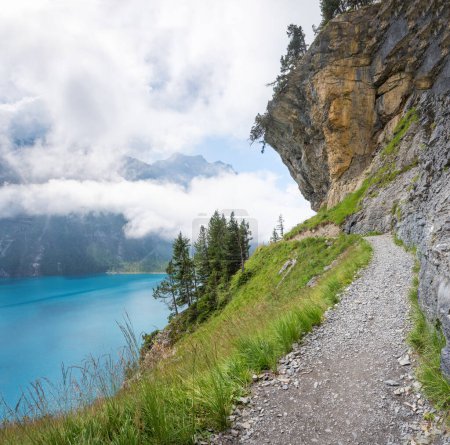 Sentier de randonnée au-dessus du lac Oeschinensee, sous les rochers en surplomb d'une paroi rocheuse escarpée. Danger de chutes de roches et d'avalanches de débris